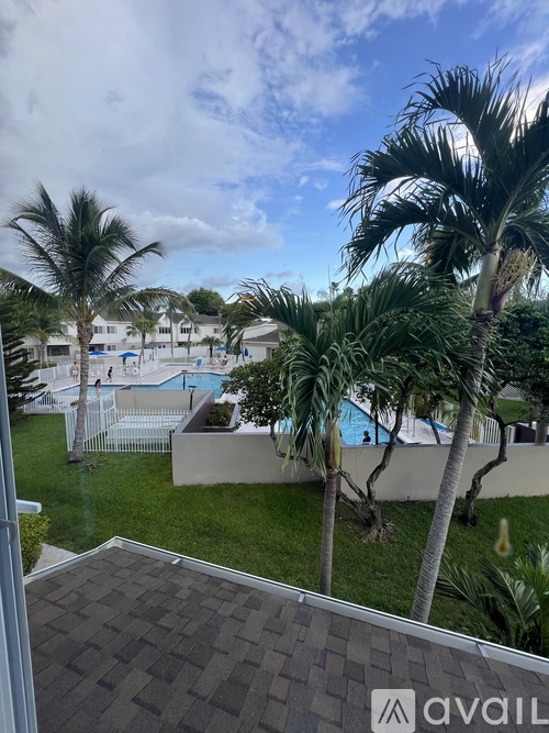 A view from a window looking out at a pool and palm trees.