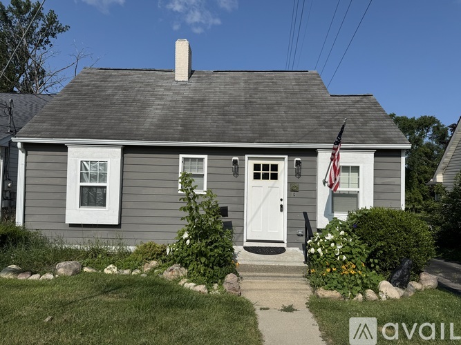 A small house with a white door and an American flag hanging on the front.