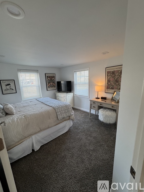 A bedroom with a bed, desk, and window with blinds.