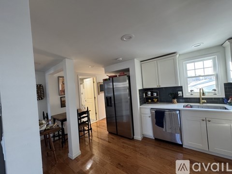 A kitchen with white cabinets and a wooden floor.