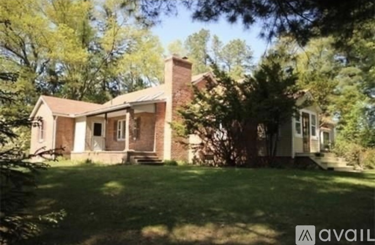 A house with a brown roof and a white door is surrounded by trees.