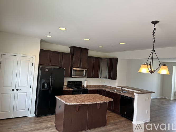 A kitchen with brown cabinets and a black fridge.