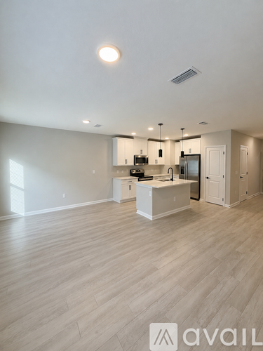 A spacious kitchen with wooden flooring and modern appliances.