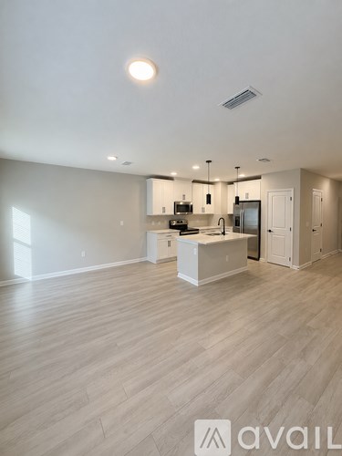 A spacious kitchen with wooden flooring and modern appliances.