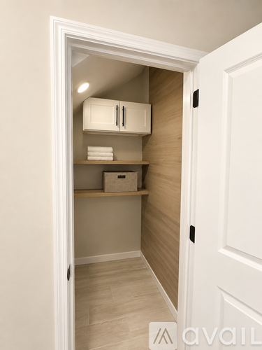 A white door opens to a small pantry with a white cabinet and a shelf.