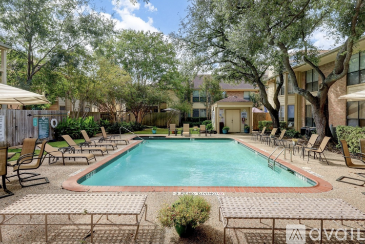 A pool surrounded by chairs and trees with a building in the background.