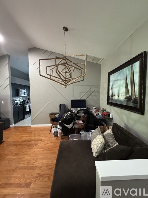 A living room with a brown couch and a hanging geometric light fixture.