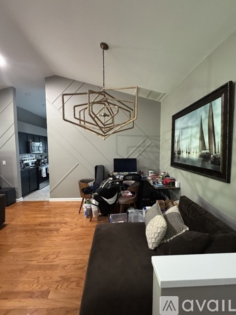 A living room with a brown couch and a hanging geometric light fixture.