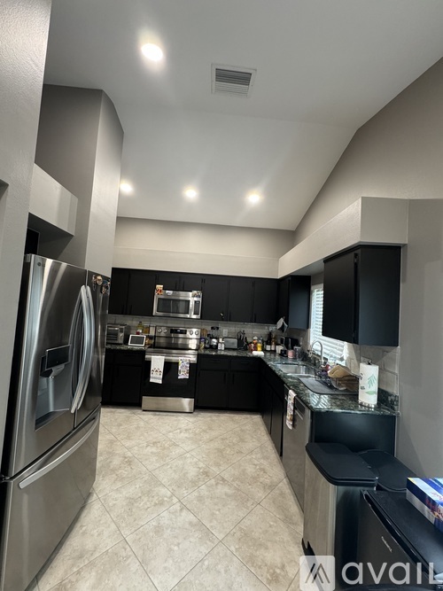 A modern kitchen with a stainless steel refrigerator and black cabinets.