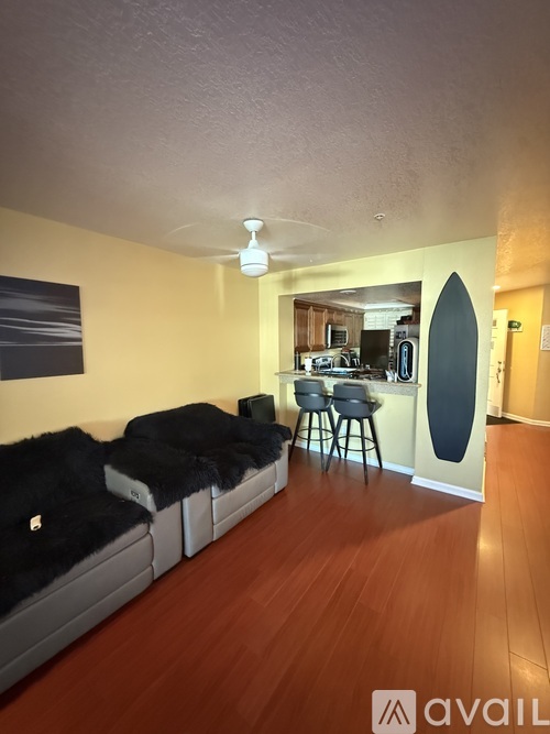 A living room with a couch and a surfboard leaning against the wall.