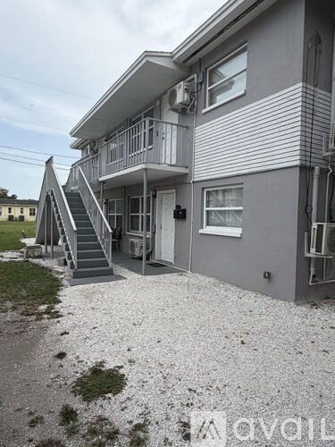 A grey house with a staircase leading to the second floor.