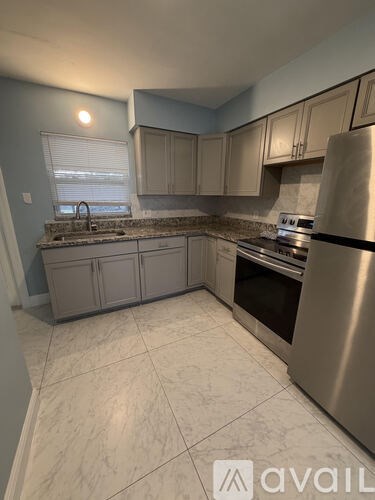 A kitchen with a stainless steel refrigerator and a marble countertop.