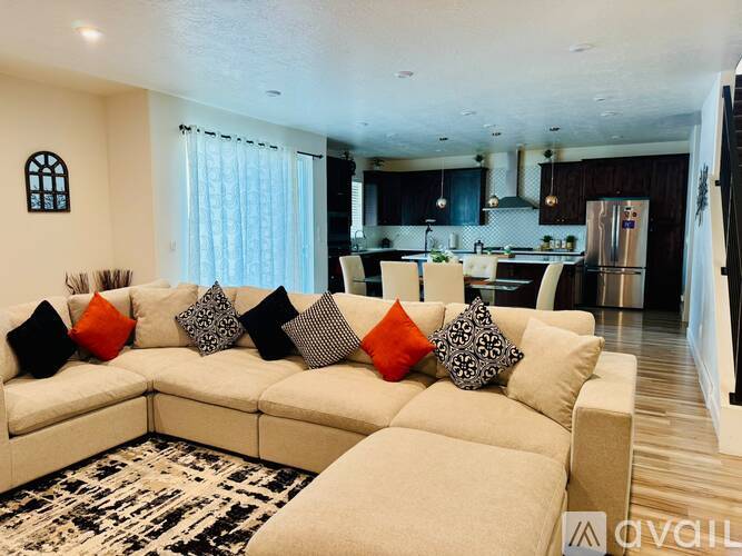 A modern living room with a large sectional sofa and a kitchen in the background.