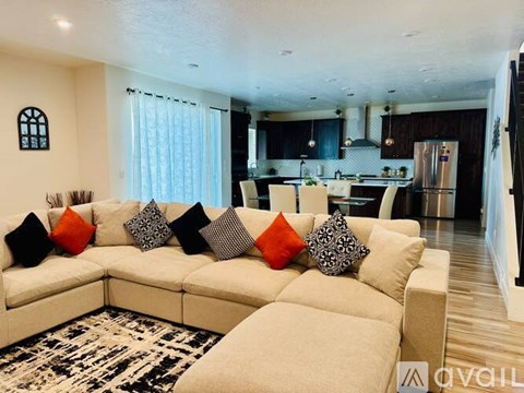 A modern living room with a large sectional sofa and a kitchen in the background.