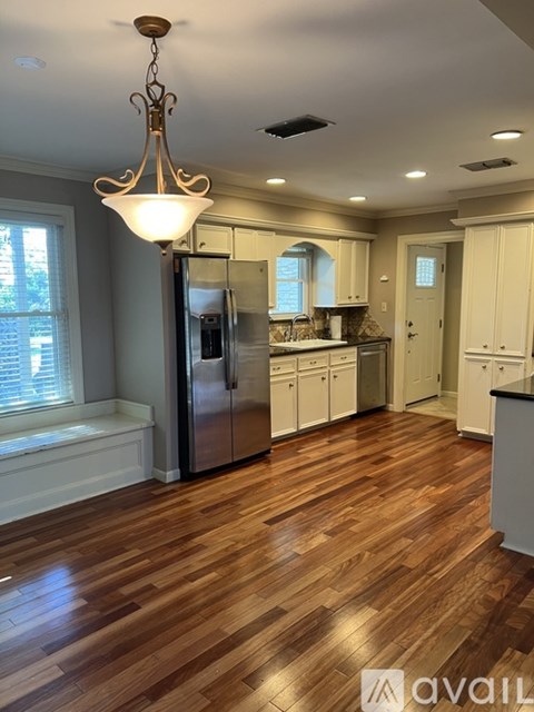 A kitchen with wooden floors and a chandelier hanging from the ceiling.