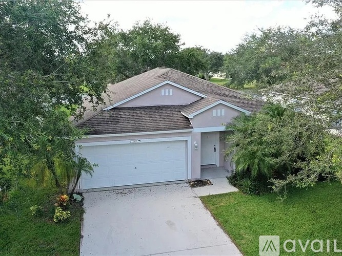 A house with a garage is surrounded by greenery.