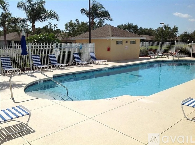 A pool with a white fence and blue and white striped chairs.