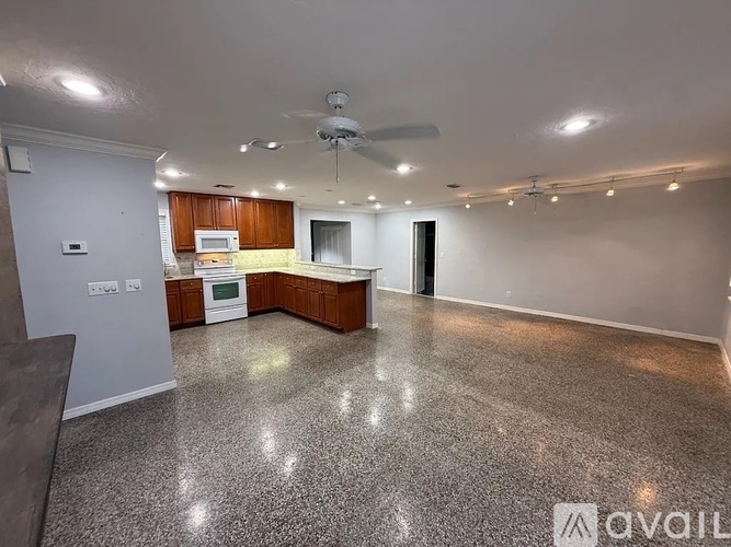 A spacious living room with a kitchenette and a ceiling fan.