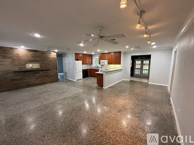 A spacious room with a kitchenette and a ceiling fan.