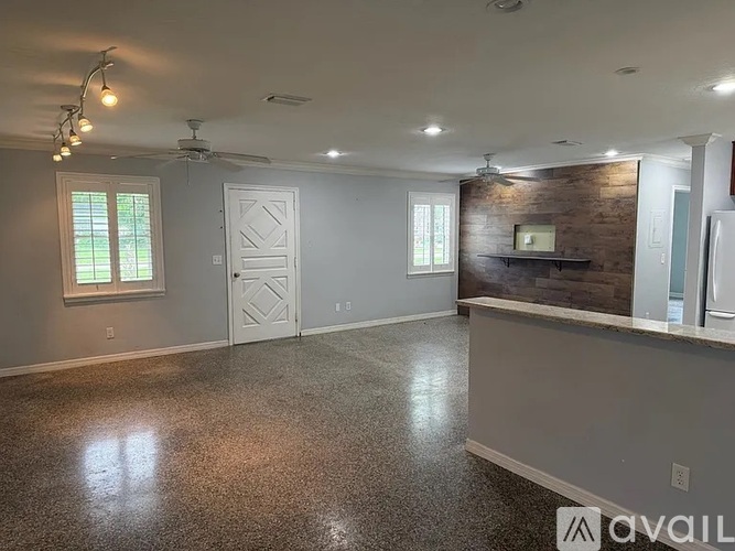 A spacious room with a ceiling fan and a brick wall.