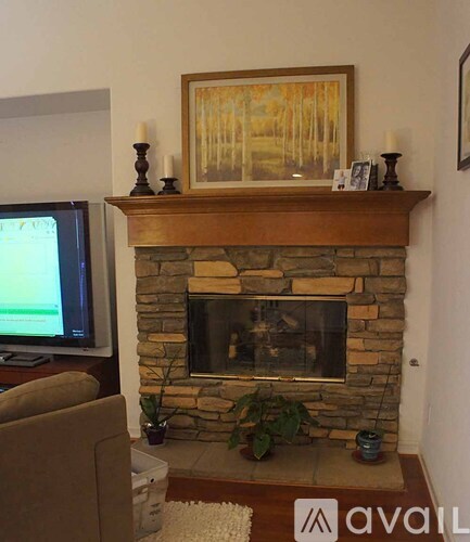 A living room with a stone fireplace and a painting above it.