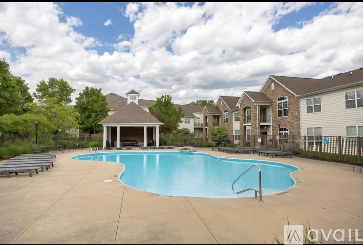 A pool area with a pavilion and loungers in front of apartment buildings.
