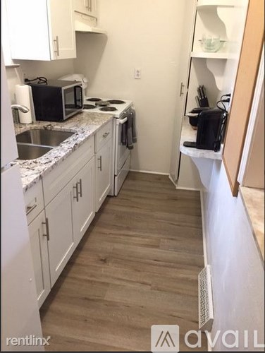 A kitchen with white cabinets and a wooden floor.