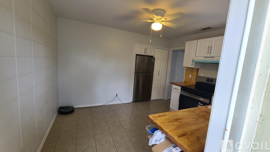 A kitchen with a wooden table and a ceiling fan.