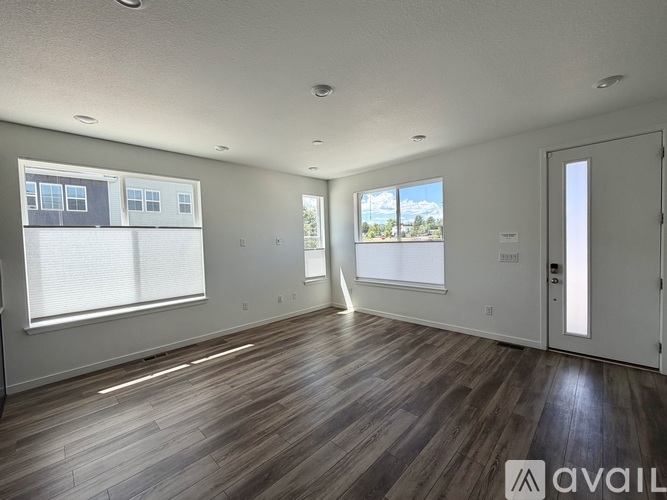 A spacious room with wooden flooring and a view of the outdoors through a window.
