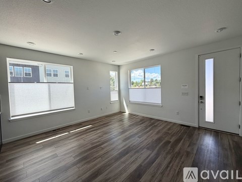 A spacious room with wooden flooring and a view of the outdoors through a window.