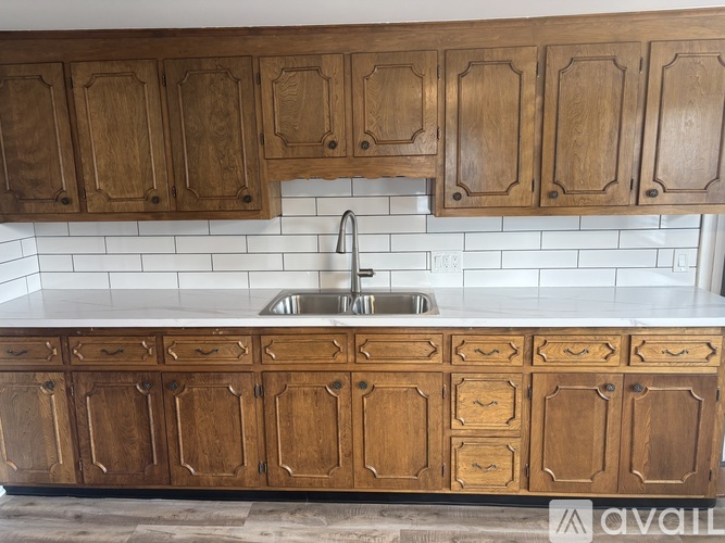 A kitchen with wooden cabinets and a white tile backsplash.