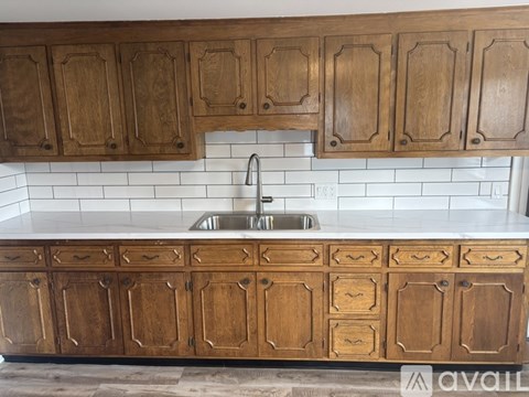 A kitchen with wooden cabinets and a white tile backsplash.