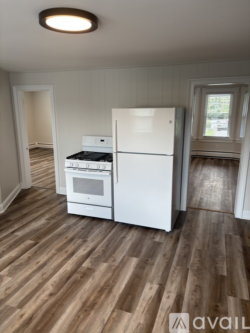 A white fridge and oven in a room with wooden flooring.
