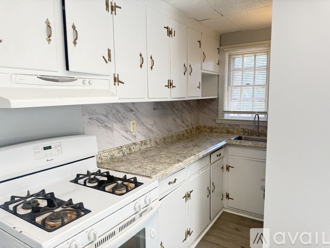 A kitchen with white cabinets and a white stove top oven.