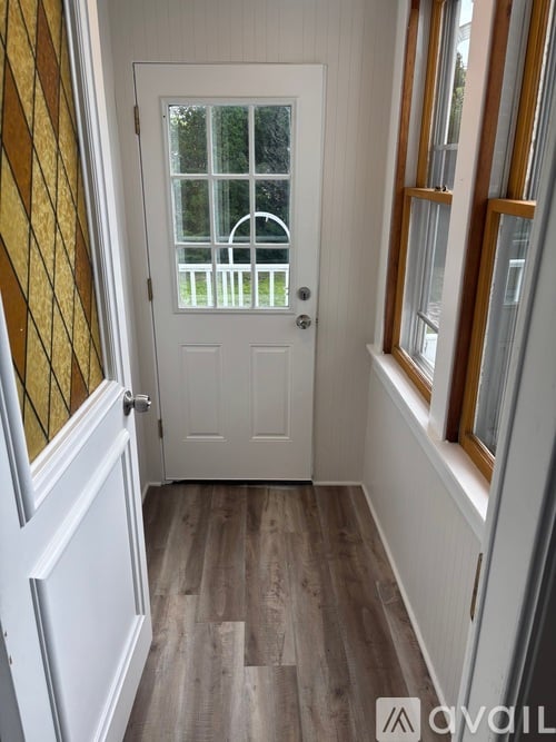 A white door with a window above it and a wooden floor.