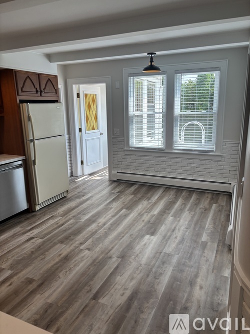 A kitchen with a refrigerator and wooden flooring.