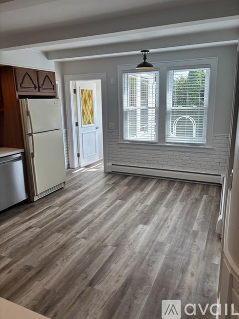 A kitchen with a refrigerator and wooden flooring.