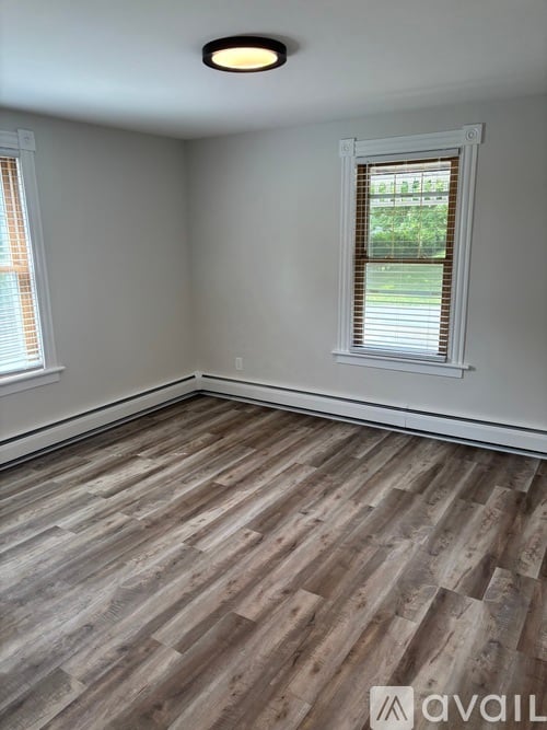 A room with wooden flooring and a window with blinds.