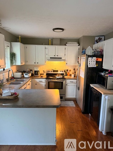 A kitchen with white cabinets and wooden floors.
