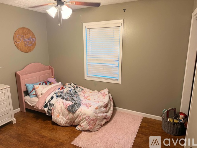 A bedroom with a pink bed and a ceiling fan.