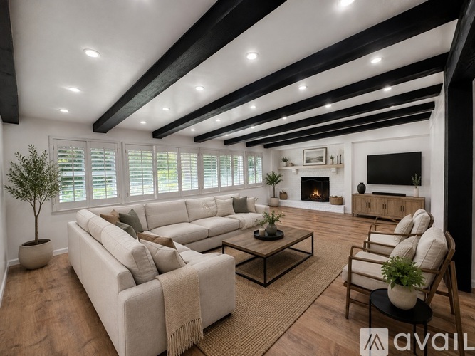 A living room with a large couch, a coffee table, and a fireplace.