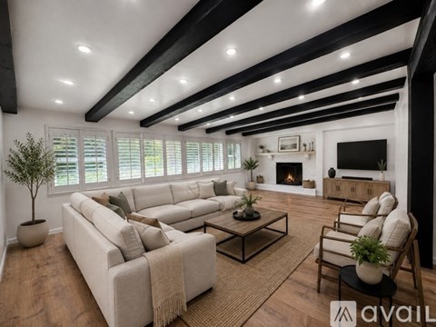 A living room with a large couch, a coffee table, and a fireplace.