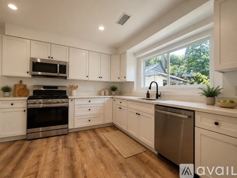 A modern kitchen with white cabinets and stainless steel appliances.
