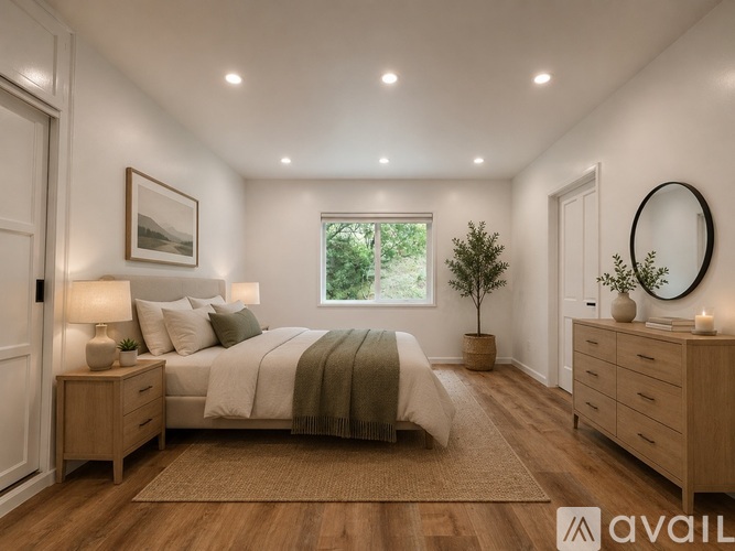 A bedroom with a large bed, a nightstand, and a dresser with a mirror.