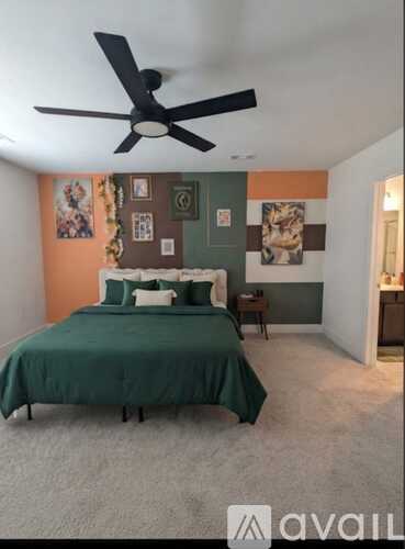 A bedroom with a bed, a ceiling fan, and pictures on the wall.