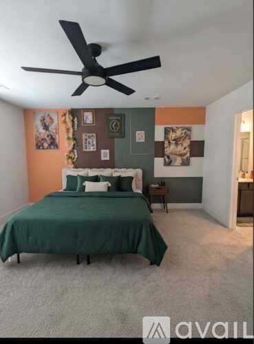 A bedroom with a bed, a ceiling fan, and pictures on the wall.