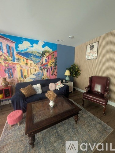 A living room with a large painting on the wall and a brown leather chair.