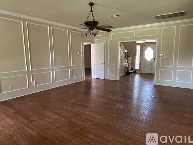 A spacious room with wood flooring and a ceiling fan.