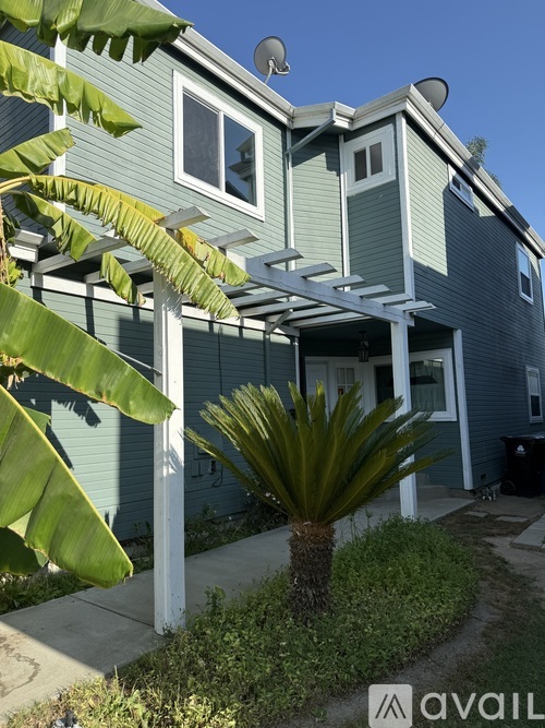 A house with a blue exterior and a white pergola.