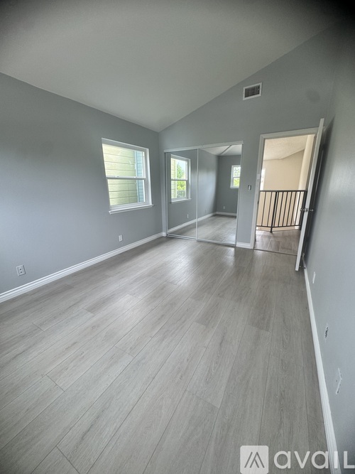 A spacious room with light grey walls and wooden flooring.
